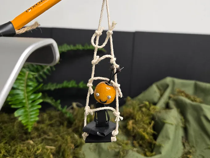 Sami est hissé par une petite échelle de corde tenue au bout d’un crayon de plomb.